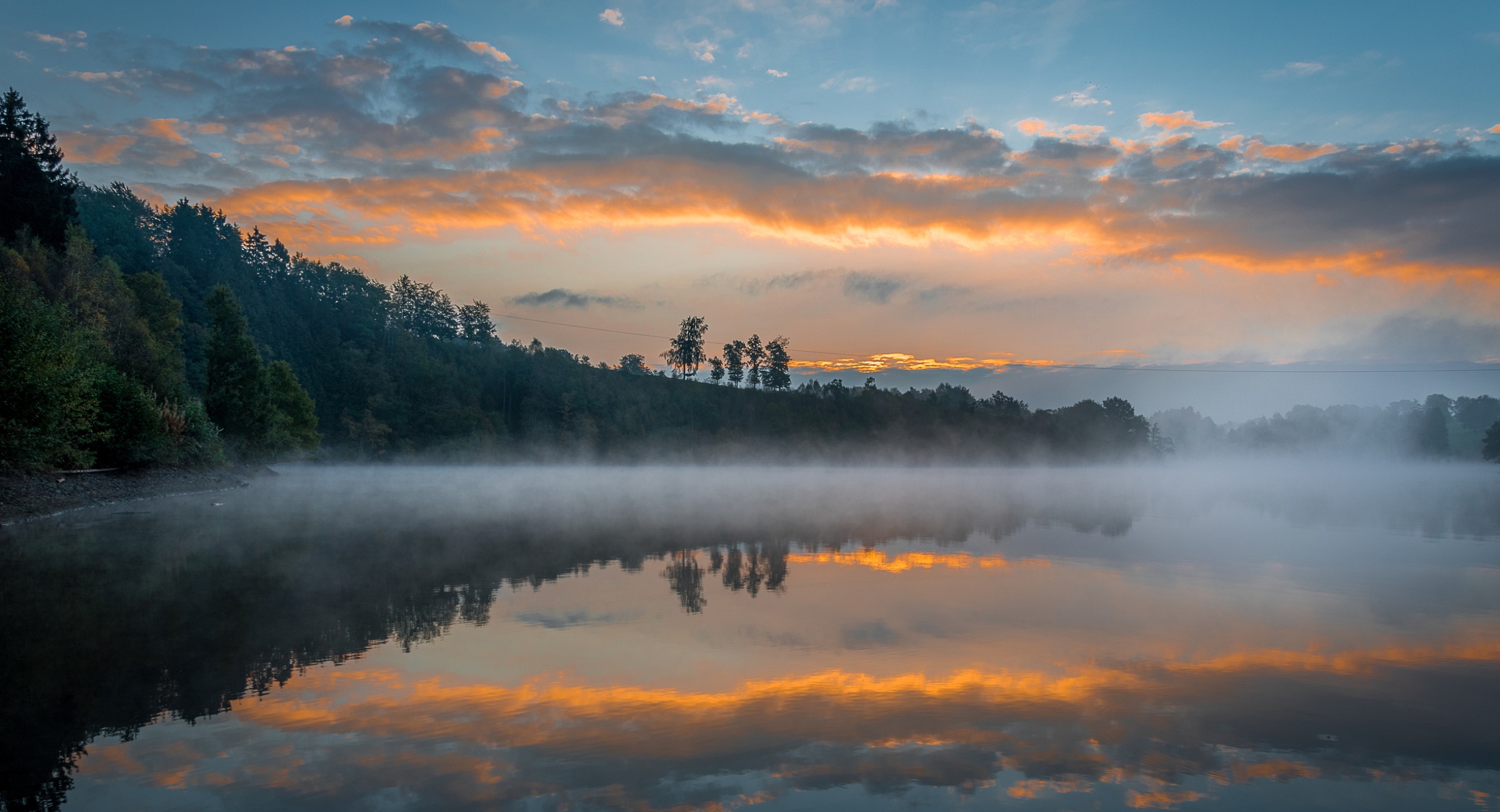 Morning mist over the water in the Belgian Ardennes